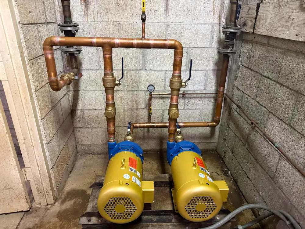 Copper piping and two booster pumps in a building's mechanical room