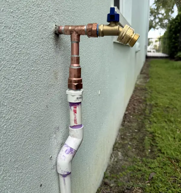 A new brass hose bibb on copper and PVC pipe on an exterior wall