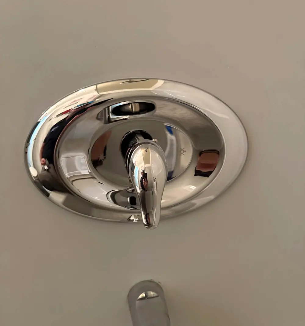 A new chrome shower valve trim installed on a tiled wall