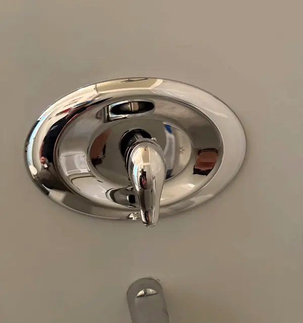 A new chrome shower valve trim installed on a tiled wall