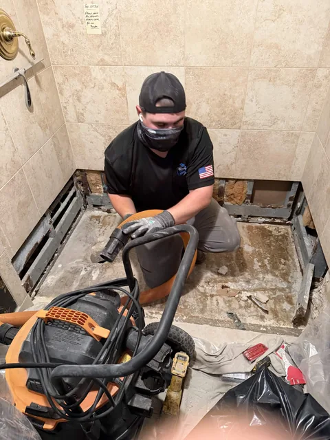 A Top Notch technician cleaning out an opened shower floor