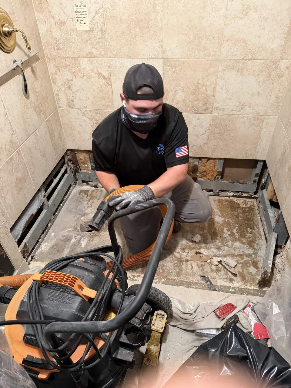 A Top Notch plumber breaking out an old shower pan in an opened-up tiled shower