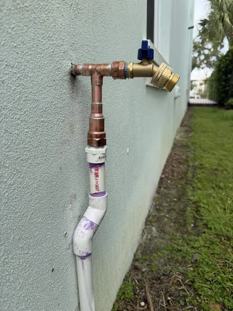 An exterior hose faucet connected to copper and PVC supply pipework